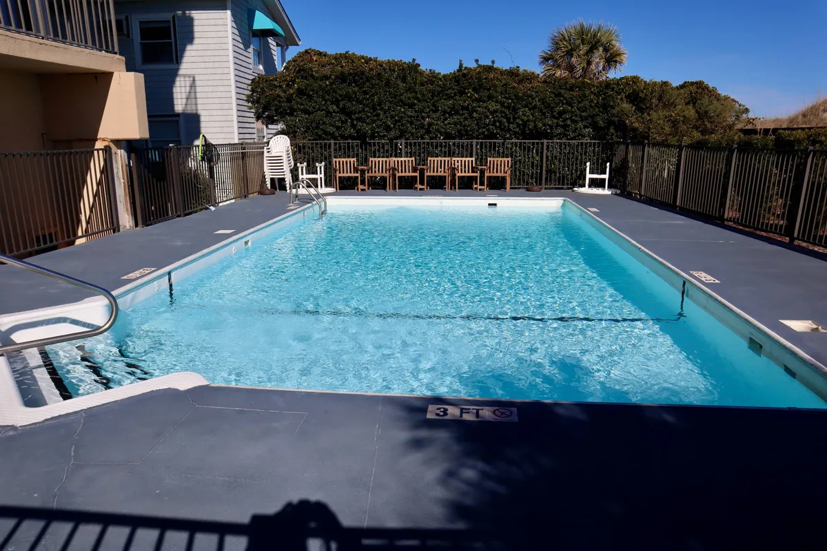 A refreshing outdoor swimming pool surrounded by lounge chairs and lush greenery, inviting guests to swim, sunbathe, or relax poolside. The pool area is clean and well-maintained, creating a resort-style ambiance.