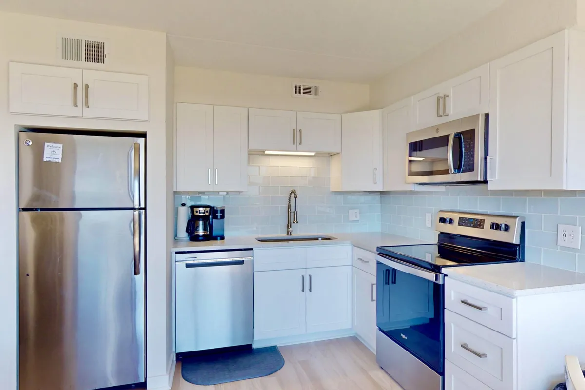 A modern kitchen featuring stainless steel appliances, a striking blue tile backsplash, and white cabinetry. The space is well-organized and inviting, ready for cooking, baking, or entertaining guests.
